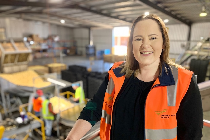 A woman wearing a high vis jacket in a potato plant.