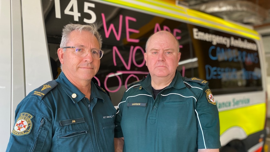 Two men in paramedic uniforms look serious.