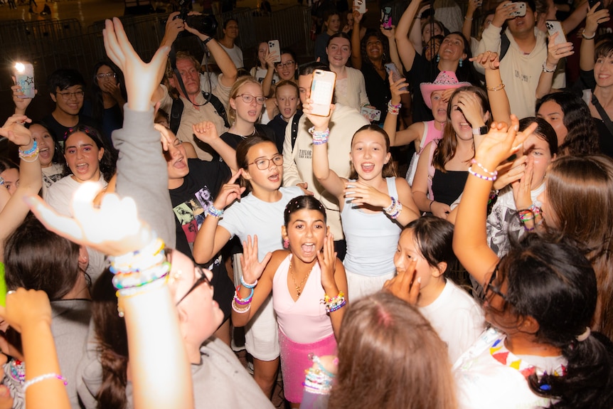 A girl in pink screams surrounded by dancing young people.
