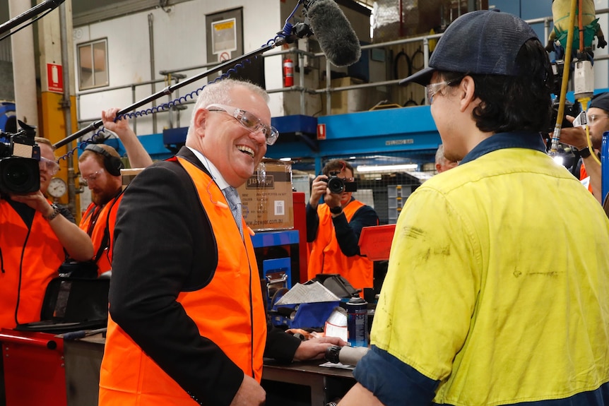 A man in a suit in a high visibility vest laughs with a another man