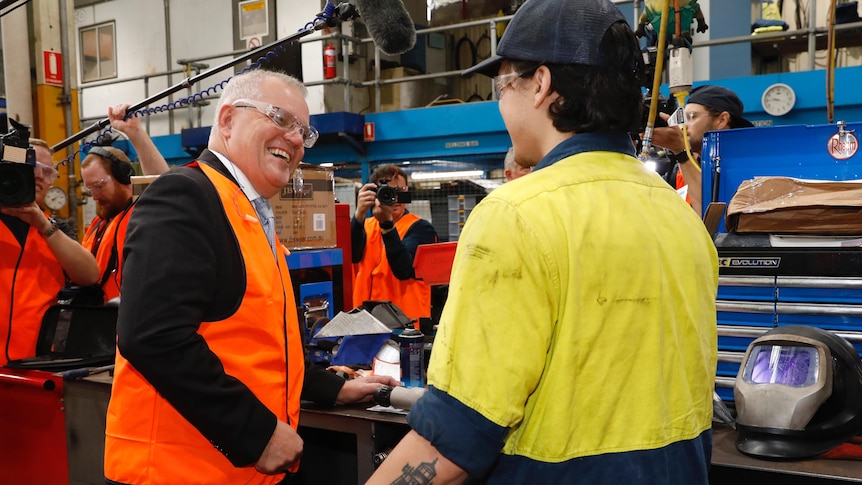 A man in a suit in a high visibility vest laughs with a another man