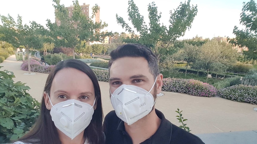 A man an a woman pose in a garden wearing P2 masks