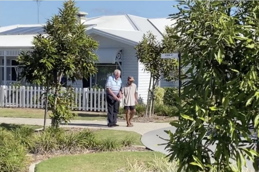 A person walks with an elderly man through an aged care facility designed to look and feel like a small town.