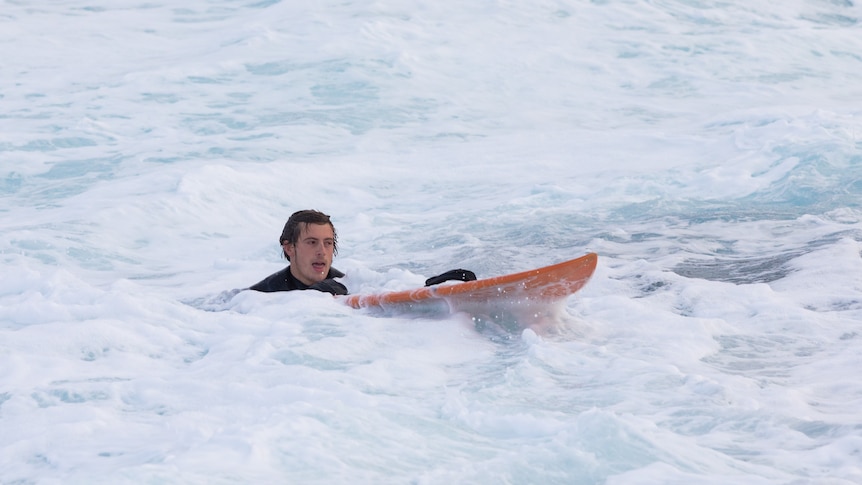 Harry Holmer-Cross and his surfboard in white water.