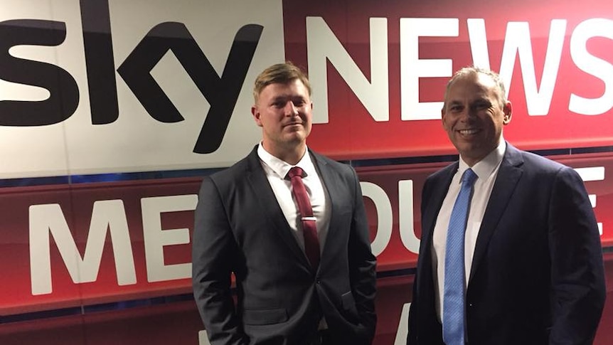 Blair Cottrell and Adam Giles standing in front of a massive Sky News banner