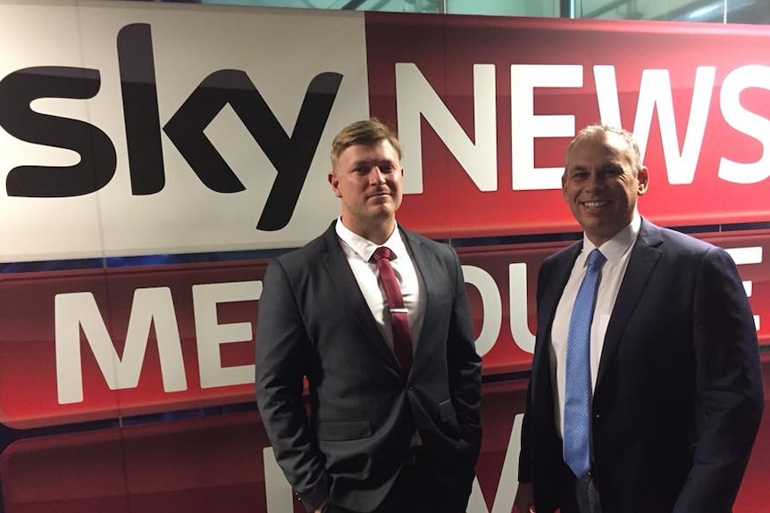 Blair Cottrell and Adam Giles standing in front of a massive Sky News banner