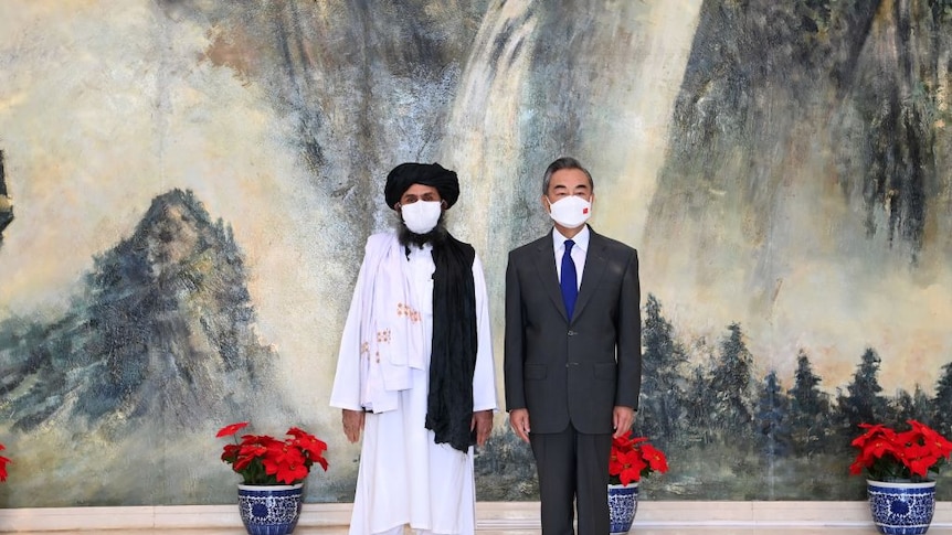 The Chinese foreign minister and head of the Taliban standing together after a meeting in July of this year.