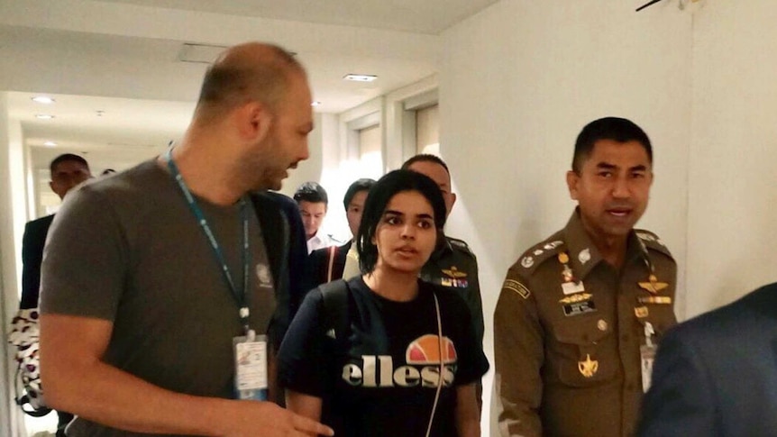 Saudi woman Rahaf Mohammed Alqunun walks through the airport with police.
