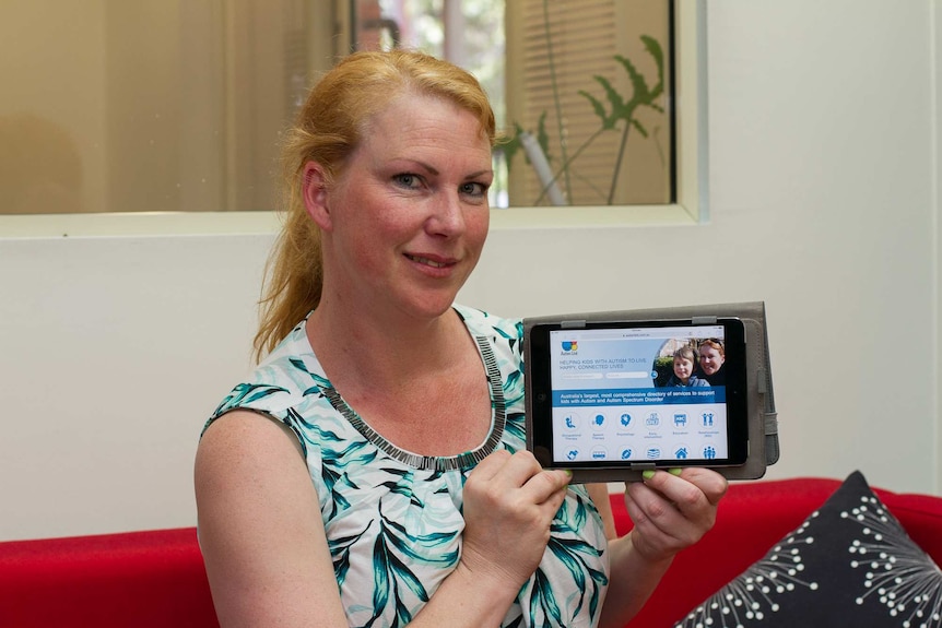 A woman holding a tablet showing a website on it