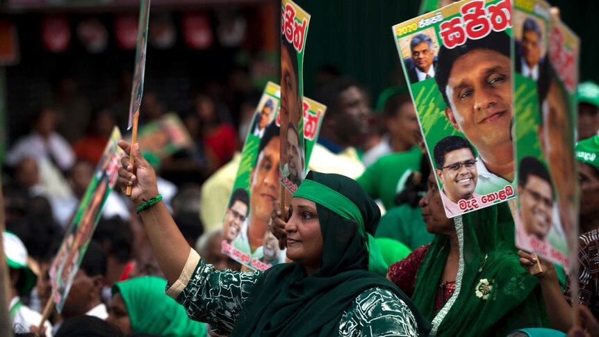 Supporters of Sri Lanka's United National Front hold placards of its 2019 Presidential candidate and are wearing green clothes.