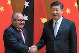 Peter O'Neill shakes hands with Xi Jinping in front of the flags of each country