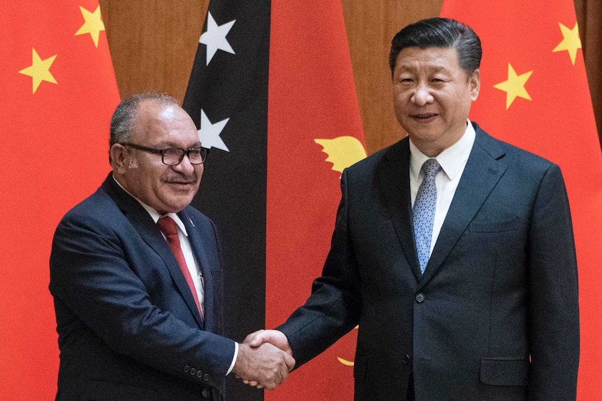 Peter O'Neill shakes hands with Xi Jinping in front of the flags of each country