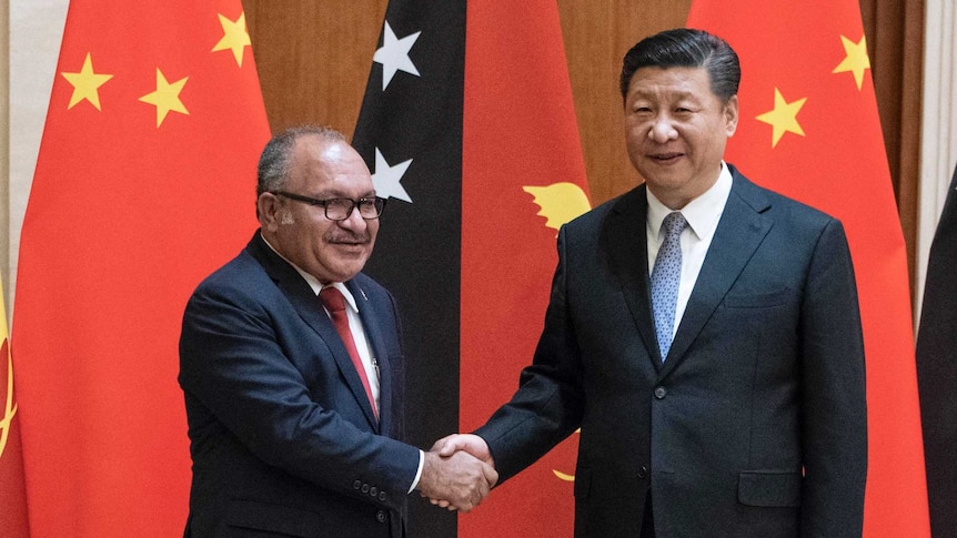 Peter O'Neill shakes hands with Xi Jinping in front of the flags of each country