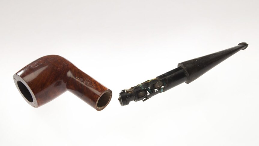 Against a grey backdrop, you see a radio receiver concealed in a smoking pipe.