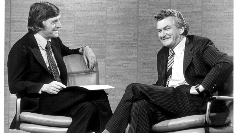A black and white photo of presenter Michael Parkinson (left) interviewing Bob Hawke (right) on his TV show.