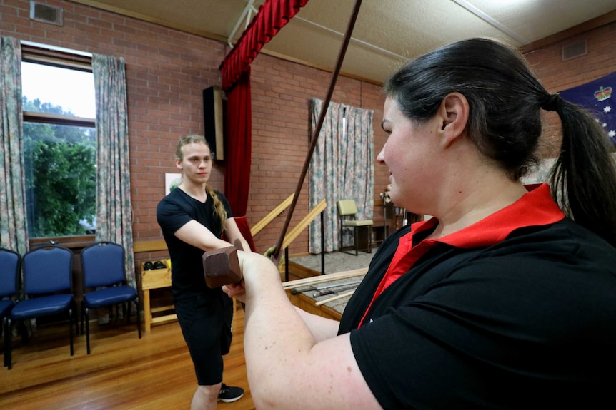 A man and a woman fight with wooden swords in a seniors hall in Ballarat