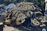A large pile of cables are piled up next to each other in a car park.