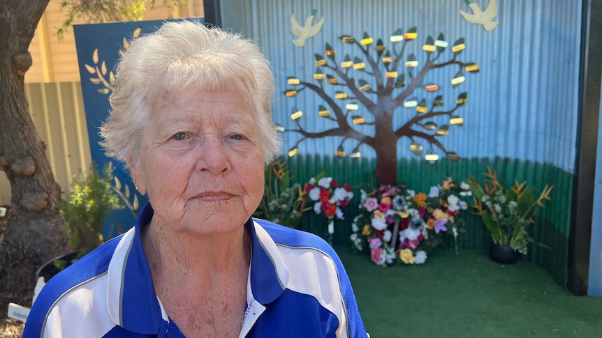 A woman standing in front a metal tree memorial for victims of asbestos exposure. 