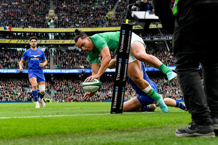 James Lowe dives for the corner holding the ball with one hand and his foot dragging in touch