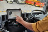 Man touching a touchscreen mobile device while sitting in a truck 