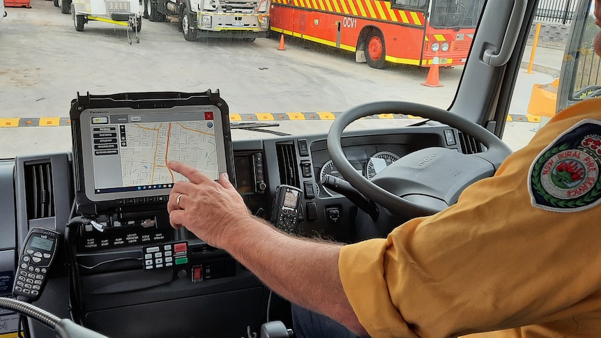 Man touching a touchscreen mobile device while sitting in a truck 