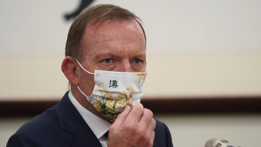 Former prime minister Tony Abbott sits behind a mic as he waits to speak in a meeting with the Taiwanese president.