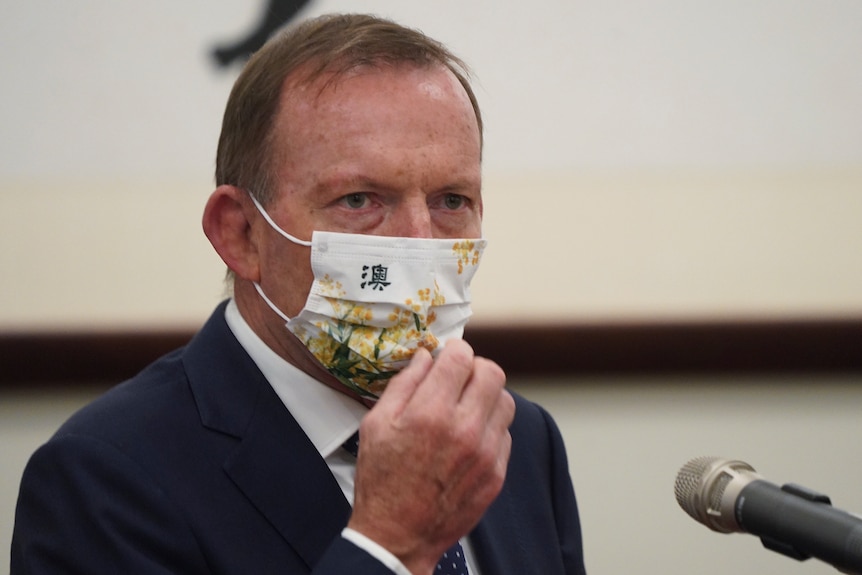 Former Prime Minister Tony Abbott sits behind a microphone while waiting to speak in a meeting with the Taiwanese president.