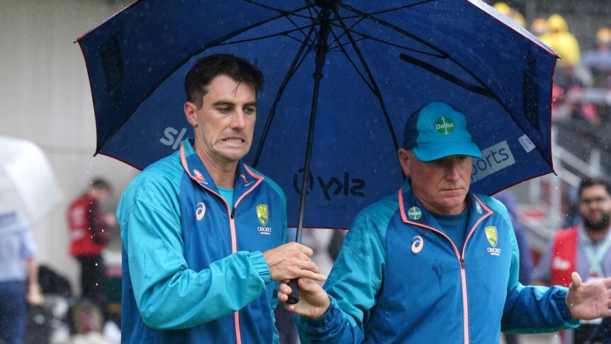 Australia captain Pat Cummins pulls a face while holding an umbrella at Old Trafford.