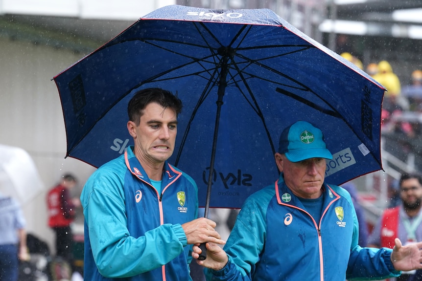 Australia captain Pat Cummins pulls a face while holding an umbrella at Old Trafford.