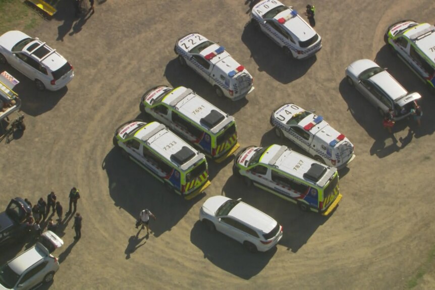 Upwards of ten emergency vehicles parked close together.