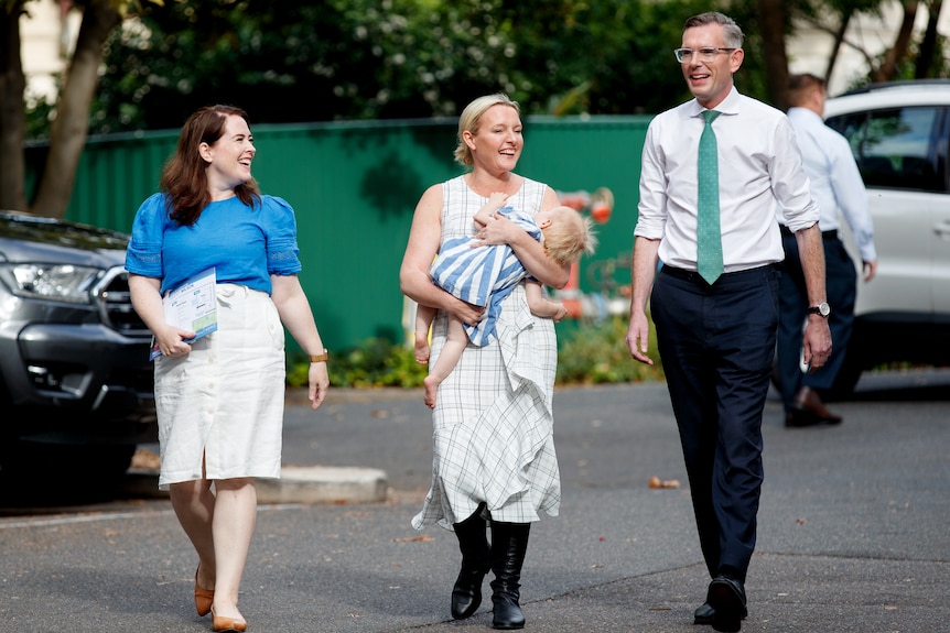 Three people walking, one woman holding baby