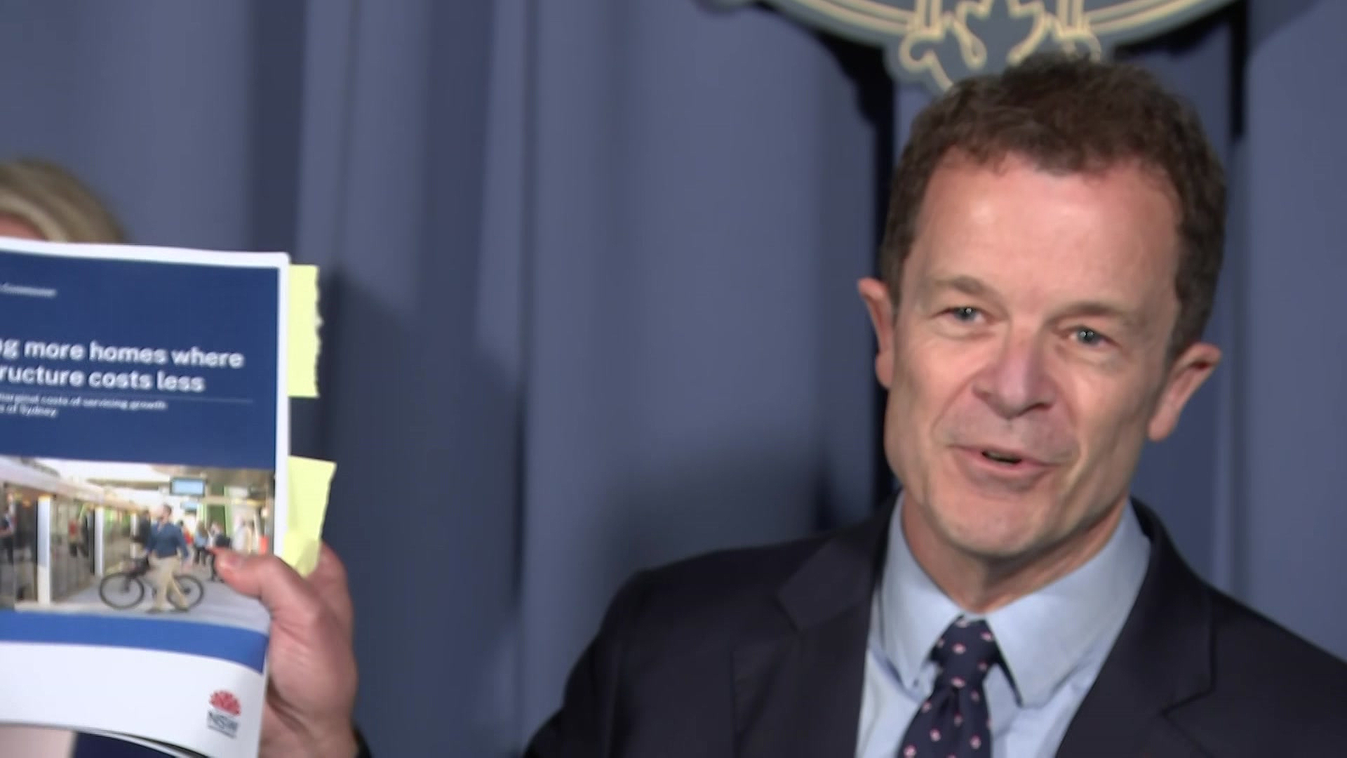 Man in suit holds a report with sticky notes hanging out