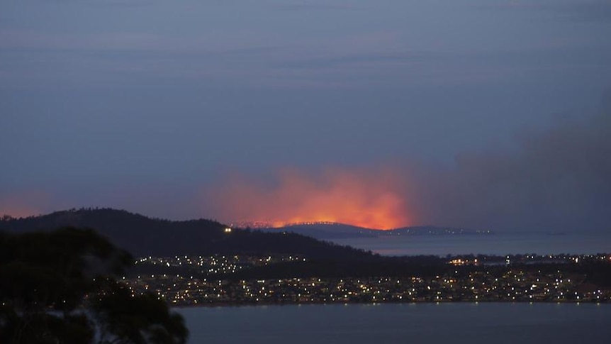 An archival photo shows the city lights of Dunalley with an orange glow surrounding the area