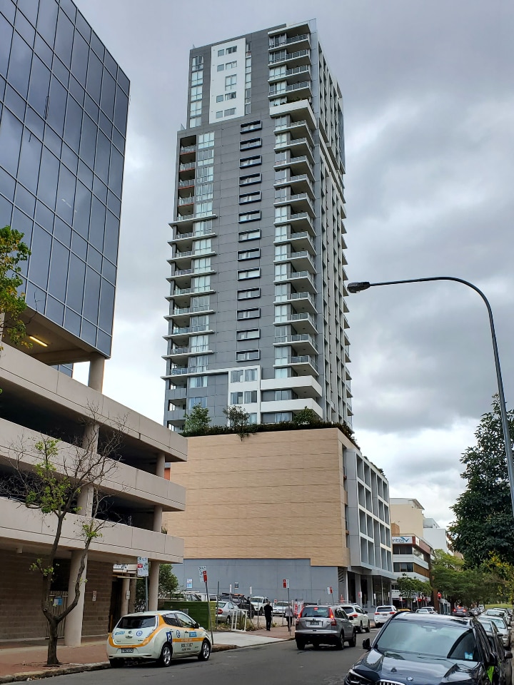 A tall residential building, pictured from street level
