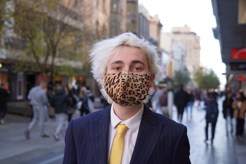 A young man in a suit wearing a mask