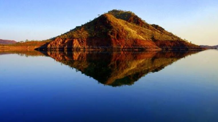 A reflection of a hill over a lake.