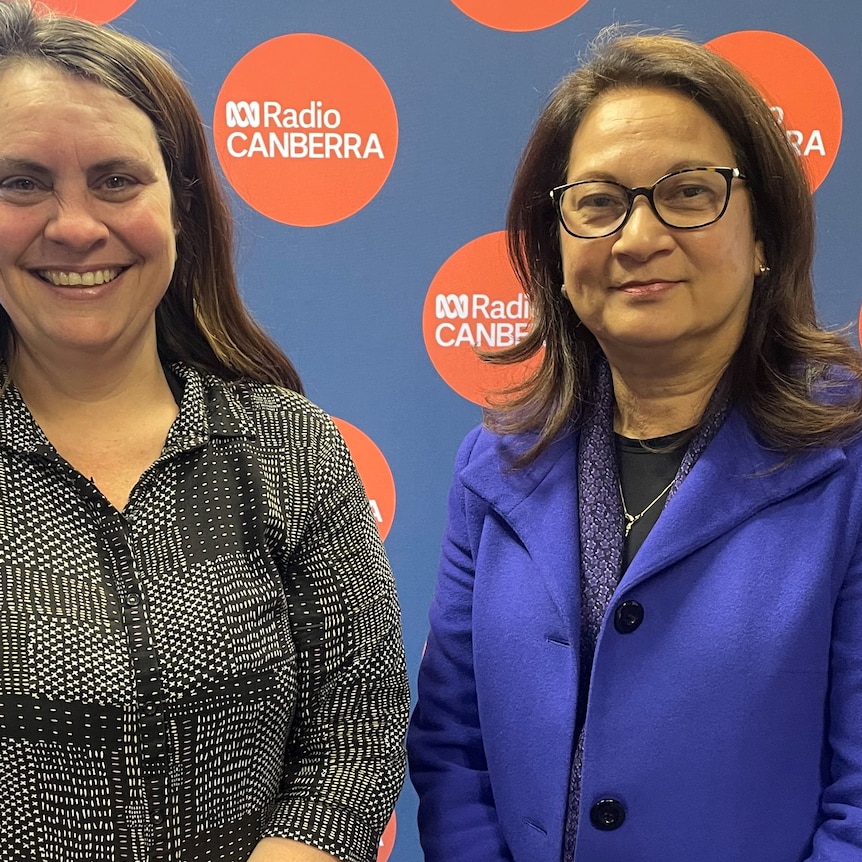 Two women stand in front of an ABC backdrop smiling