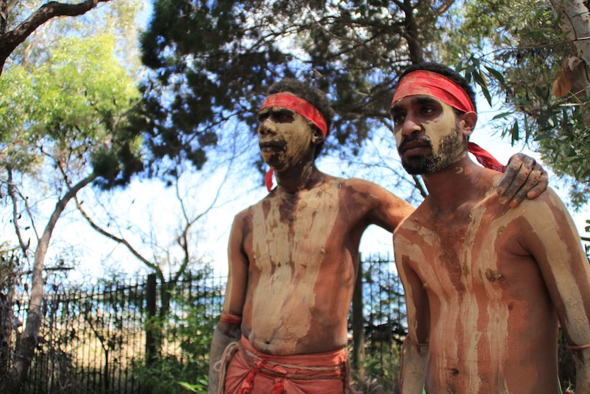 Traditional owners in Butchalla stand together wearing traditional Aboriginal dress with body paint