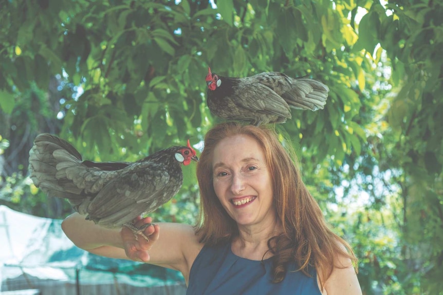 Fiona Scott-Norman with two of her chickens in a backyard, who regularly lay fresh eggs.