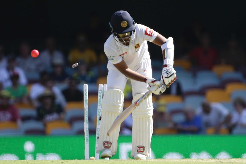 Sri Lankan batsman stands at the crease as the ball and the bails fly off at the Gabba.