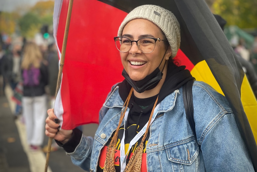 Una donna tiene una bandiera aborigena durante una manifestazione.