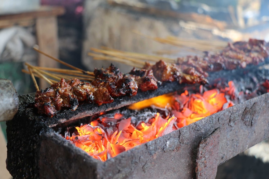 Satay sticks cooking on a BBQ.