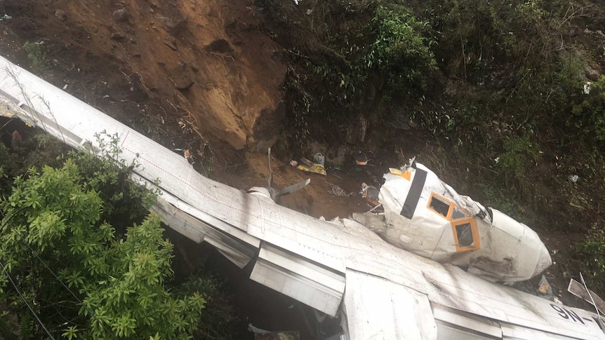 The wreckage of a plane is seen in mountainous terrain.