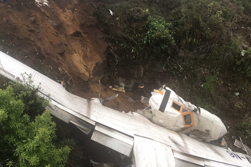 The wreckage of a plane is seen in mountainous terrain.