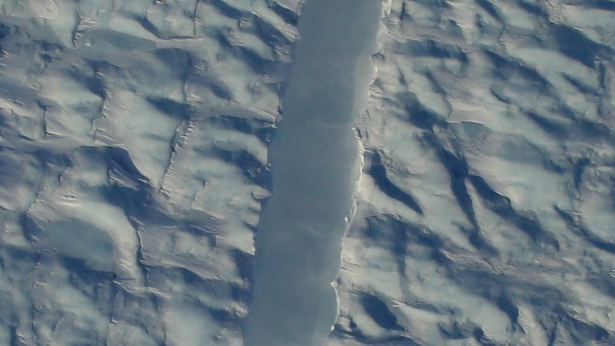 An aerial view of a chasm running through an ice shelf.