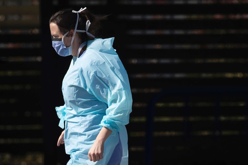 A hospital worker wearing blue scrubs and a face mask.
