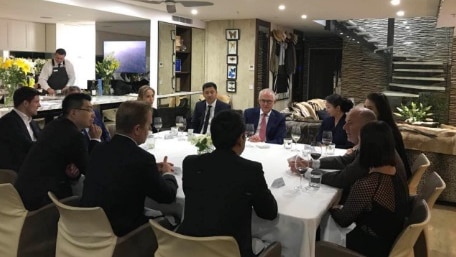 People sit around a dinner table. Malcolm Turnbull is sitting next to Liu Xiaodong.