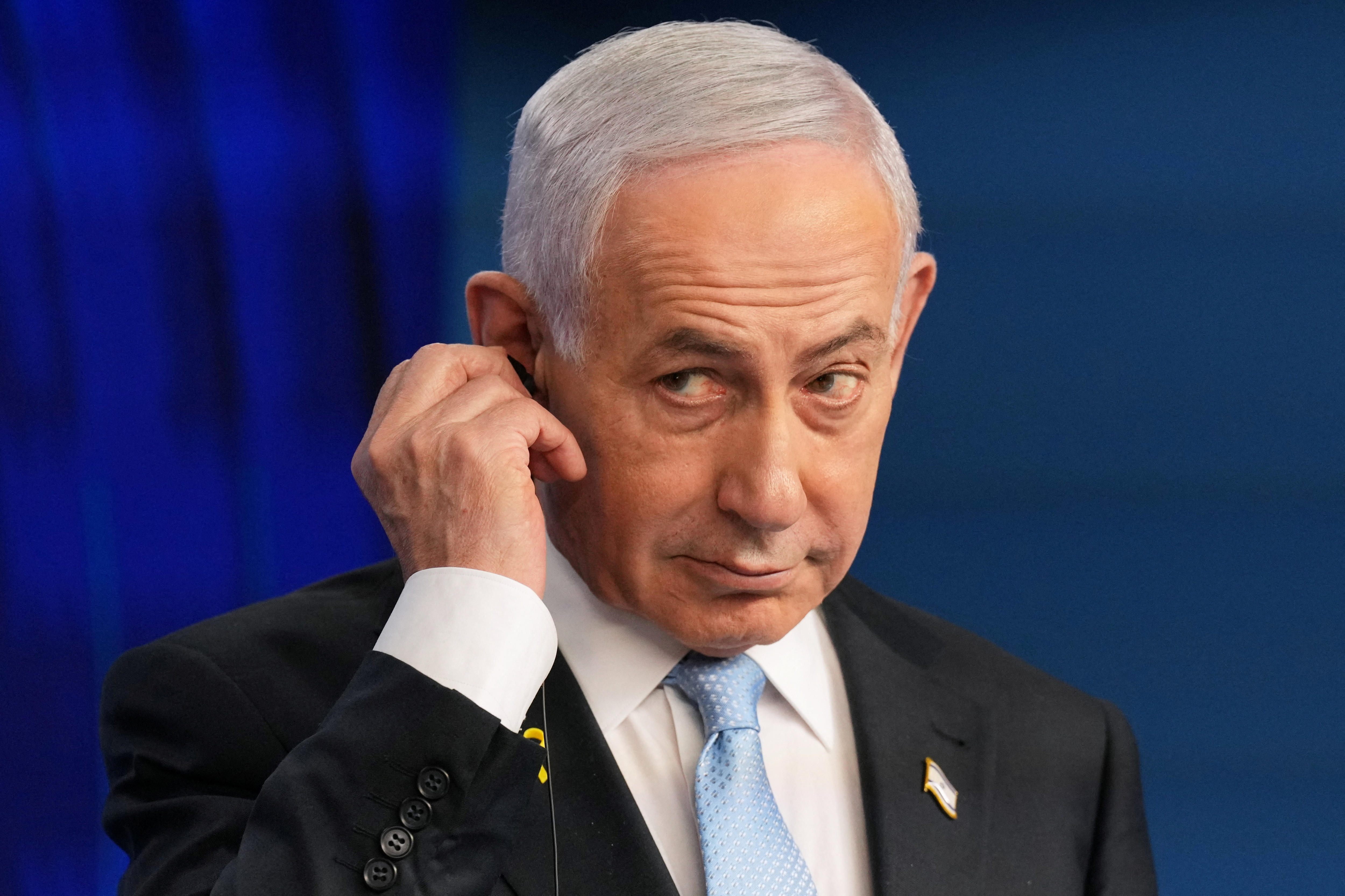 Netanyahu mira hacia arriba mientras se ajusta un auricular.