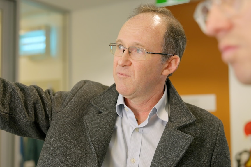 Veterinary virologist Dr Andrew Read pointing at a screen.