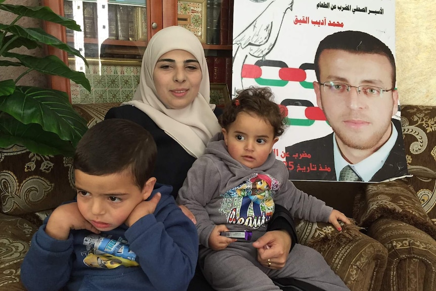 Faihaa Shalash, wife of Palestinian journalist Mohammad al-Qeeq, sitting on a couch with their kids.